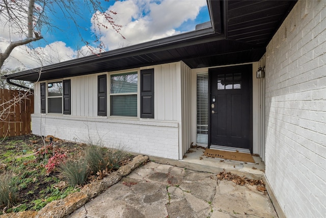 property entrance with brick siding and fence