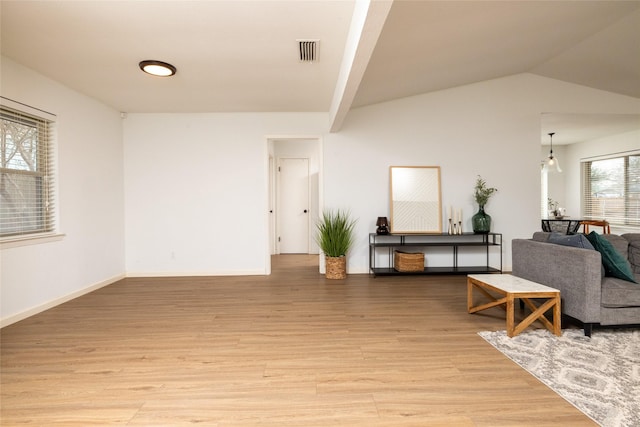 living area featuring lofted ceiling, light wood-style flooring, visible vents, and baseboards