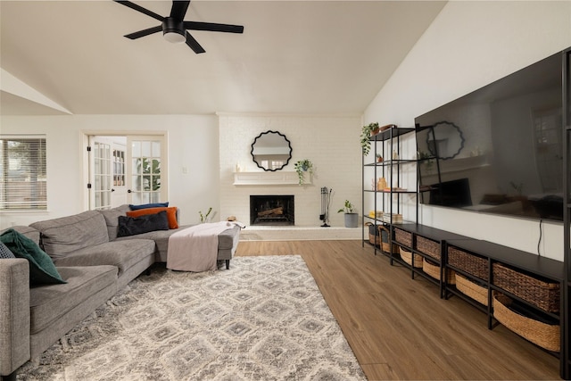 living room featuring a wealth of natural light, a brick fireplace, lofted ceiling, and wood finished floors