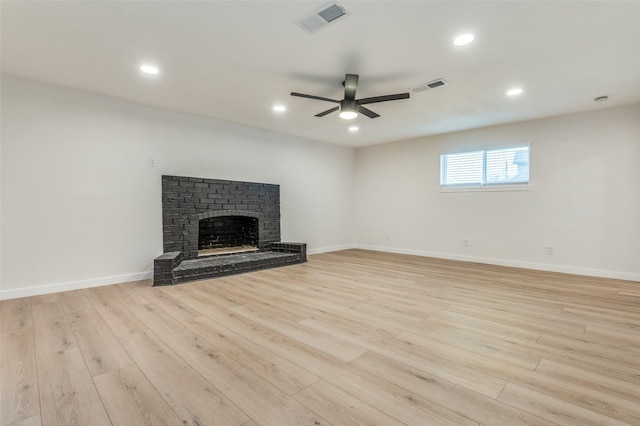 unfurnished living room with a ceiling fan, visible vents, a fireplace, and light wood-style flooring