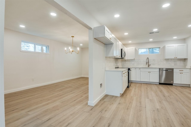 kitchen featuring appliances with stainless steel finishes, light wood-type flooring, a sink, and decorative backsplash