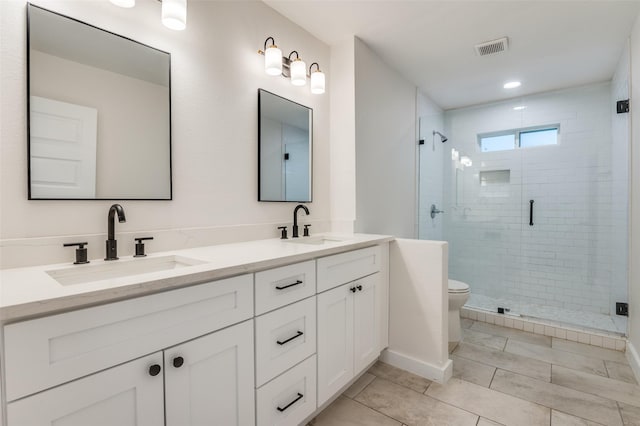 full bathroom with toilet, a stall shower, a sink, and visible vents