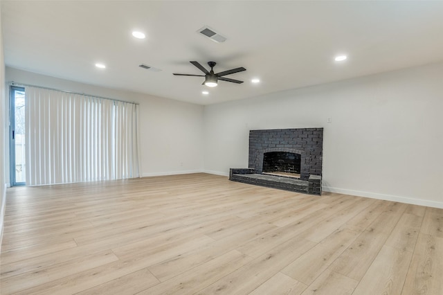 unfurnished living room featuring a ceiling fan, a fireplace, visible vents, and light wood-style floors