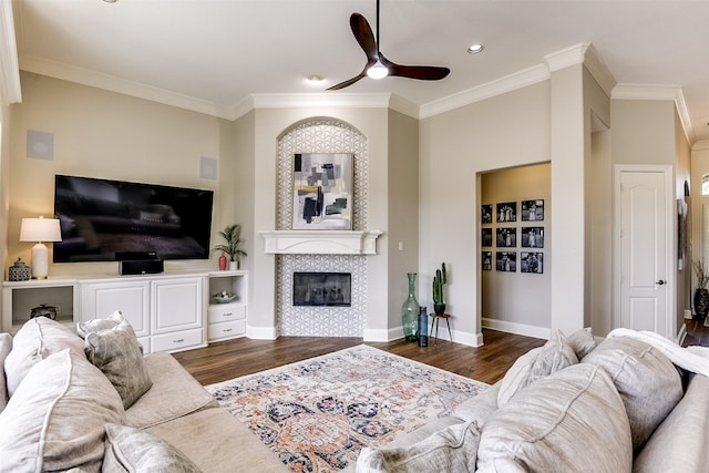 living area featuring baseboards, ornamental molding, a tiled fireplace, and wood finished floors