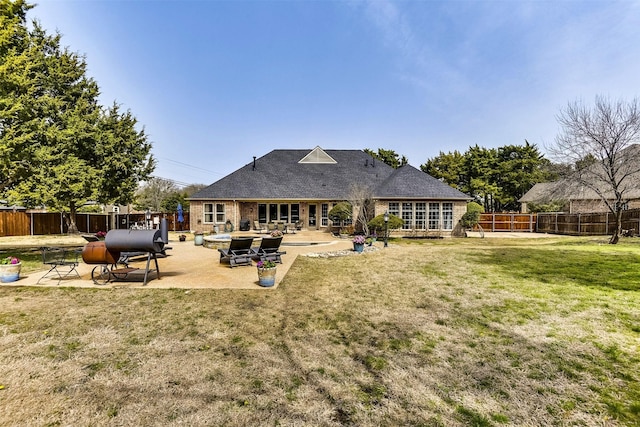 rear view of property featuring brick siding, a fenced backyard, a lawn, and a patio