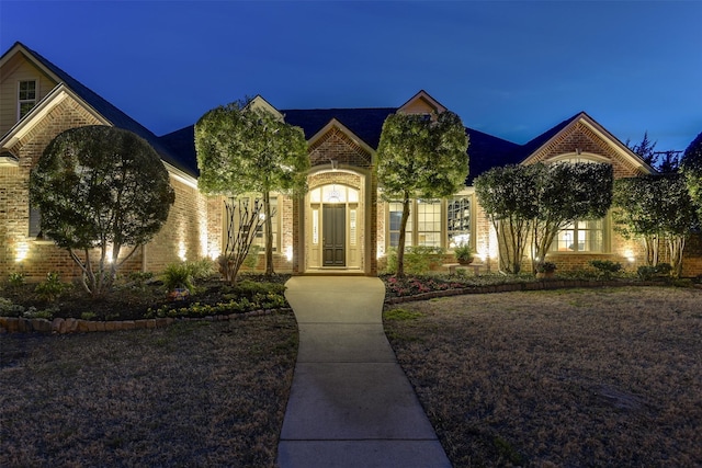 french country home featuring brick siding