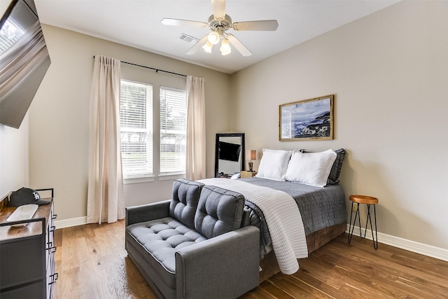 bedroom featuring light wood-style floors, visible vents, baseboards, and ceiling fan