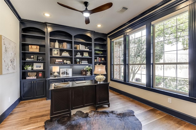 office area featuring baseboards, visible vents, a ceiling fan, crown molding, and light wood-type flooring