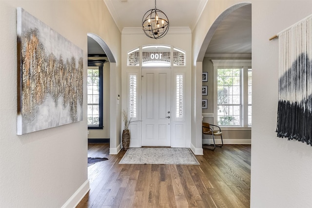 entryway with a notable chandelier, baseboards, crown molding, and wood finished floors