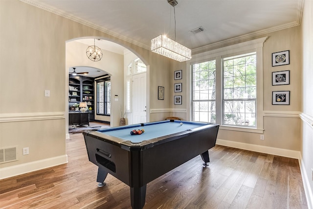 game room featuring arched walkways, ornamental molding, wood finished floors, and visible vents