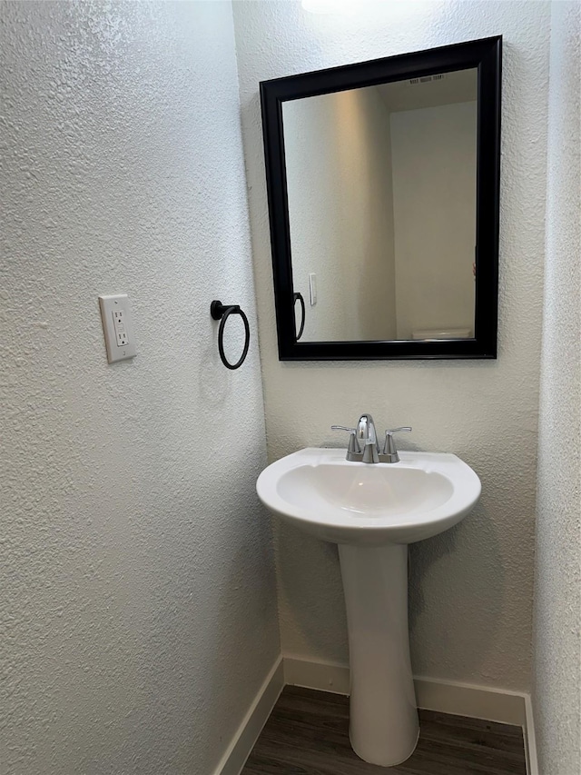 bathroom with a sink, baseboards, wood finished floors, and a textured wall