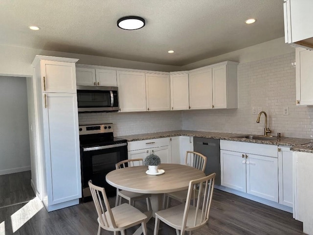 kitchen with stainless steel appliances, dark wood-style flooring, a sink, and white cabinets