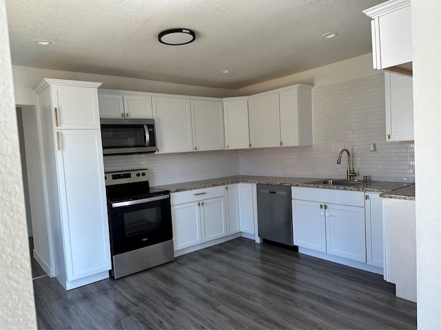 kitchen with stainless steel appliances, dark wood-type flooring, a sink, and white cabinets