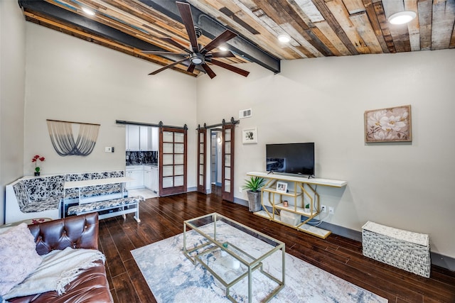 living area featuring beam ceiling, visible vents, a barn door, ceiling fan, and hardwood / wood-style floors