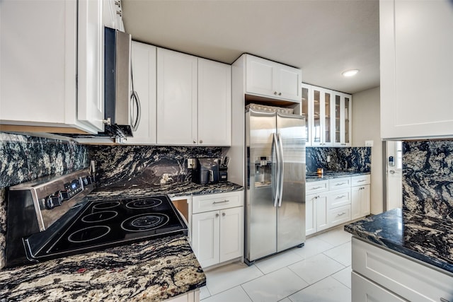 kitchen featuring dark stone counters, appliances with stainless steel finishes, backsplash, and white cabinetry