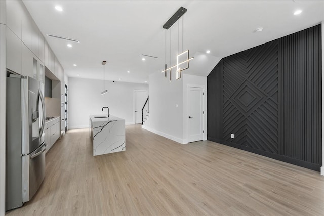 kitchen featuring an accent wall, white cabinets, light wood-type flooring, stainless steel fridge with ice dispenser, and modern cabinets