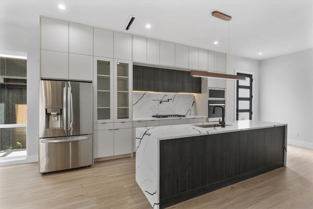 kitchen with white cabinetry, stainless steel fridge, a sink, and modern cabinets