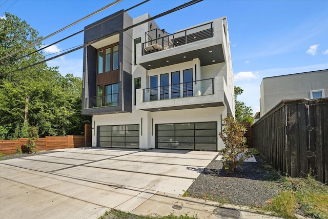 contemporary house featuring driveway, an attached garage, fence, and stucco siding