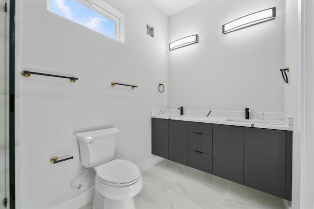 bathroom featuring marble finish floor, a sink, toilet, and double vanity