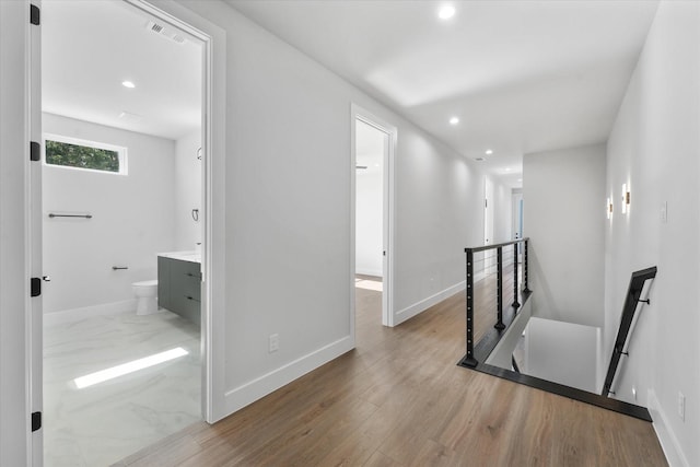 hall with recessed lighting, wood finished floors, an upstairs landing, and baseboards