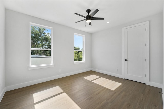 empty room with wood finished floors, a ceiling fan, and baseboards