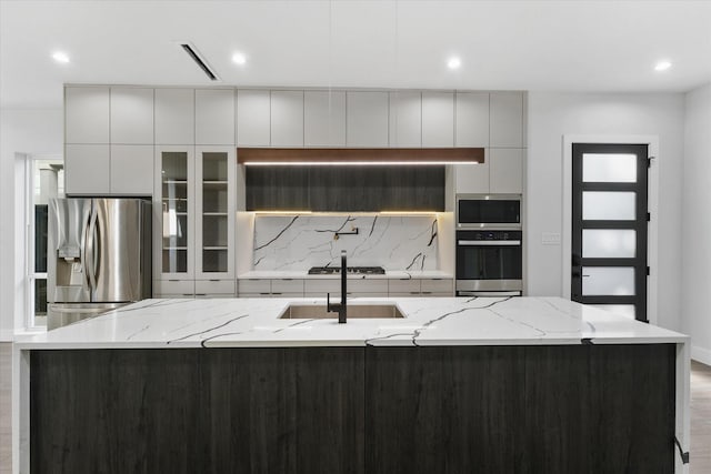 kitchen featuring an island with sink, modern cabinets, appliances with stainless steel finishes, and a sink