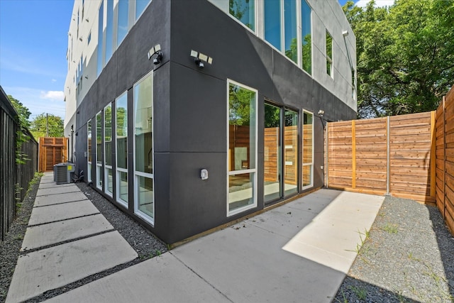 exterior space with a fenced backyard, a patio, central AC, and stucco siding