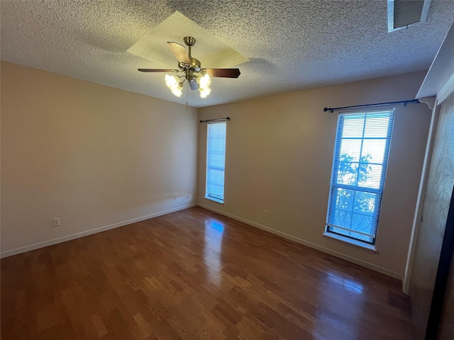 empty room with wood finished floors, visible vents, baseboards, ceiling fan, and a textured ceiling