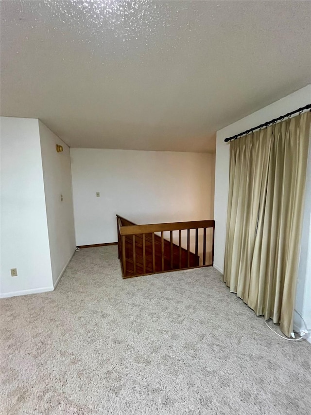 spare room with carpet flooring, baseboards, and a textured ceiling