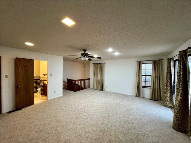 spare room with a textured ceiling, a ceiling fan, baseboards, and light carpet