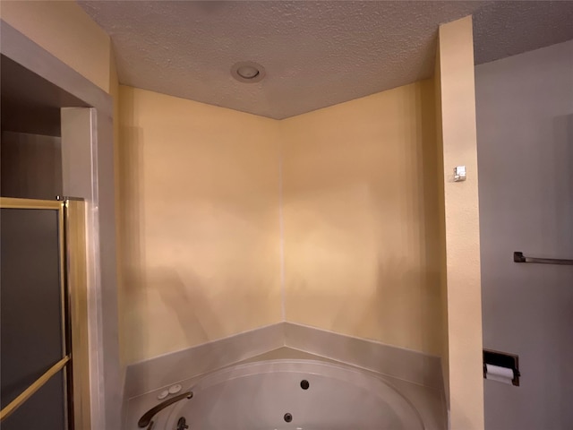 bathroom with a shower stall, a textured ceiling, and a whirlpool tub