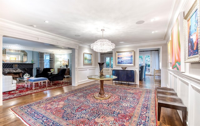 interior space with a notable chandelier, a decorative wall, ornamental molding, wainscoting, and wood finished floors