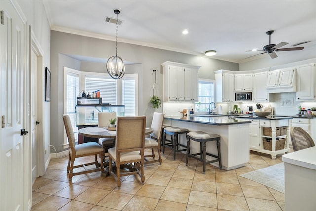 kitchen with light tile patterned flooring, a sink, visible vents, and built in microwave