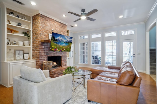 living room with a fireplace, visible vents, stairway, light wood-type flooring, and crown molding