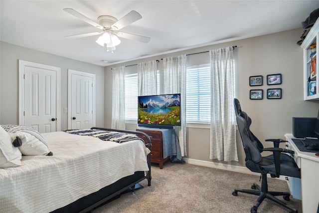 bedroom with multiple windows, light carpet, baseboards, and two closets