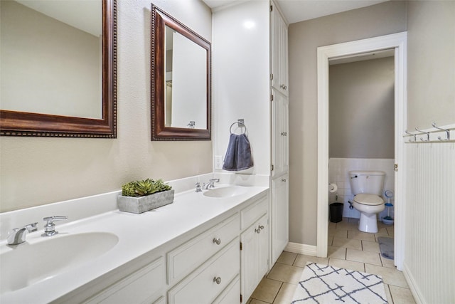 bathroom with toilet, tile patterned flooring, double vanity, and a sink