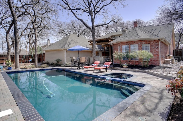 view of pool featuring a patio area, a pool with connected hot tub, and fence