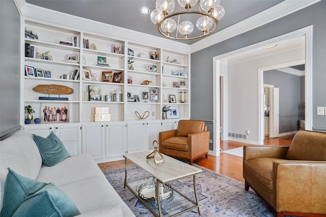 sitting room featuring baseboards, visible vents, light wood-style flooring, crown molding, and a chandelier