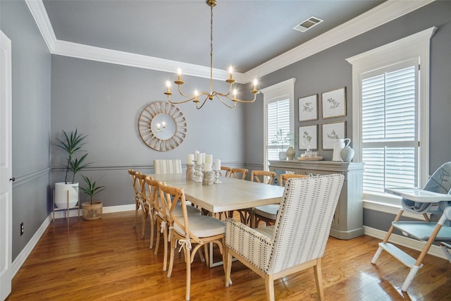 dining space featuring ornamental molding, a chandelier, light wood-style flooring, and baseboards