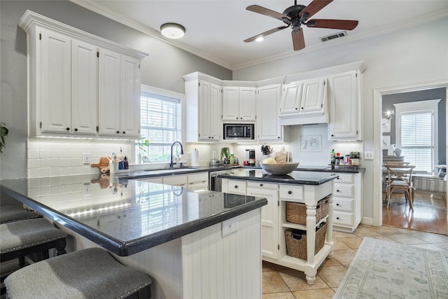 kitchen with stainless steel appliances, dark countertops, visible vents, and white cabinetry