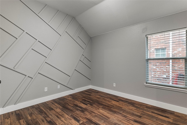 empty room featuring dark wood-style floors, baseboards, and vaulted ceiling