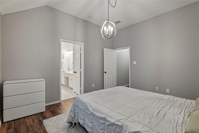 bedroom featuring lofted ceiling, connected bathroom, wood finished floors, visible vents, and an inviting chandelier