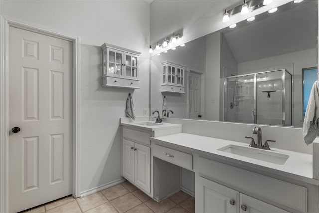 bathroom with double vanity, a sink, a shower stall, and tile patterned floors