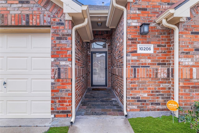 doorway to property featuring a garage and brick siding