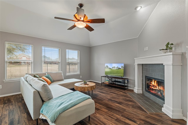 living area with lofted ceiling, baseboards, a tiled fireplace, and wood finished floors