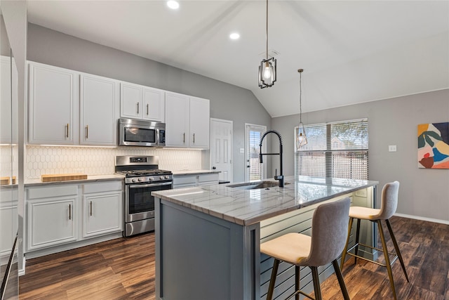 kitchen featuring a center island with sink, a breakfast bar area, stainless steel appliances, backsplash, and a sink