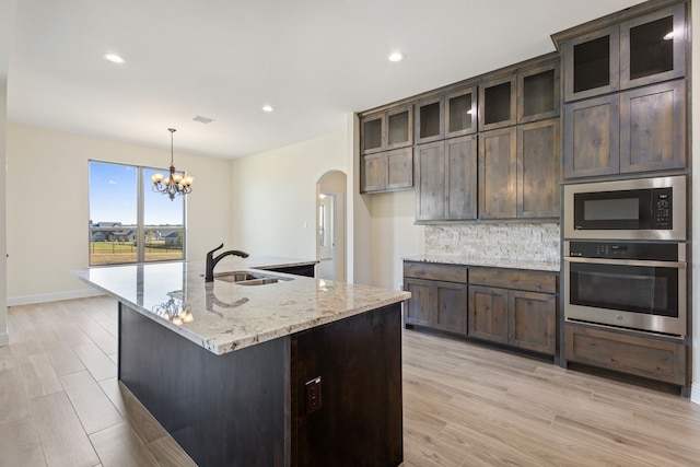 kitchen with light wood-type flooring, a sink, stainless steel oven, and built in microwave