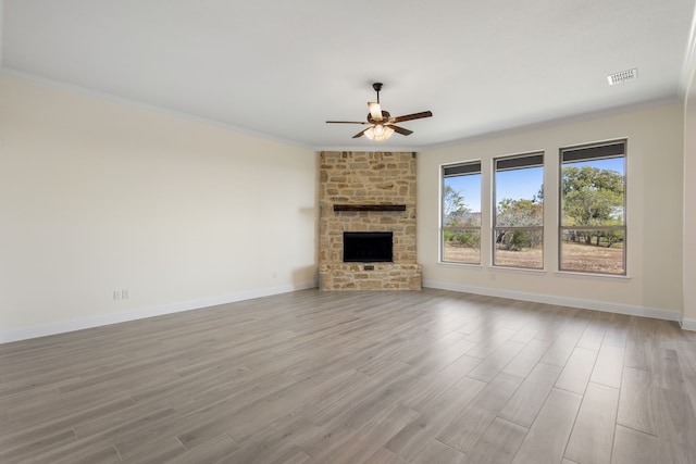 unfurnished living room featuring light wood finished floors, ceiling fan, a fireplace, and crown molding