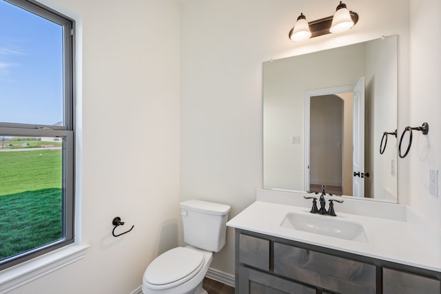 bathroom featuring toilet, baseboards, and vanity