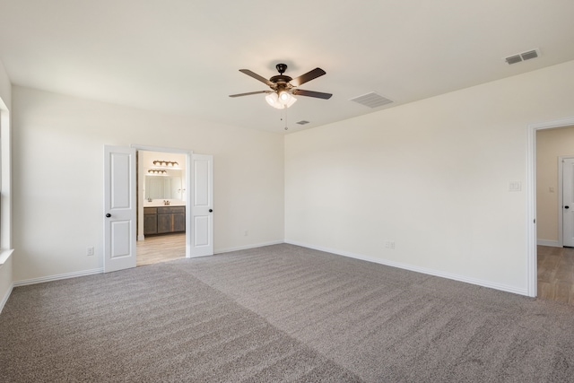 empty room featuring ceiling fan, visible vents, and light colored carpet